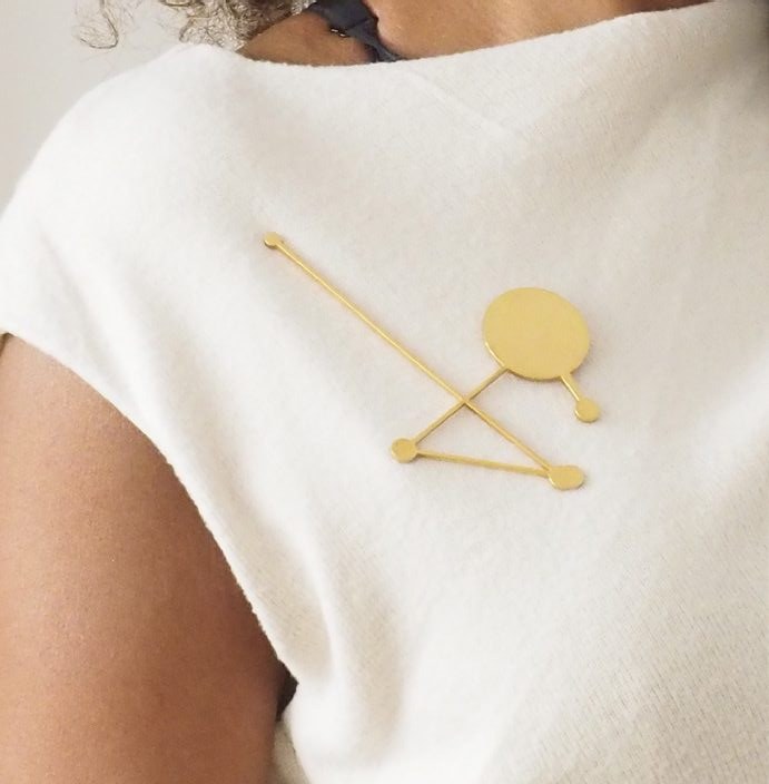 Broche constellation plaquée or portée sur un haut blanc